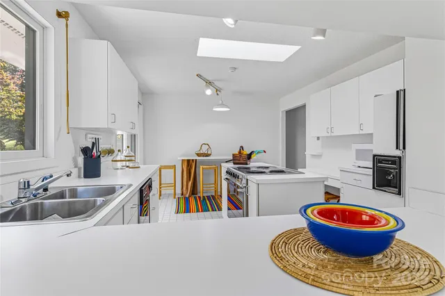 a kitchen with white cabinets and sink