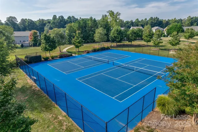 a view of a tennis ground with large trees