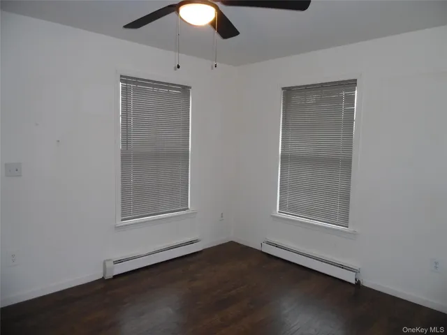 an empty room with wooden floor cabinet and windows