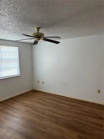 a view of a room with wooden floor a ceiling fan and windows