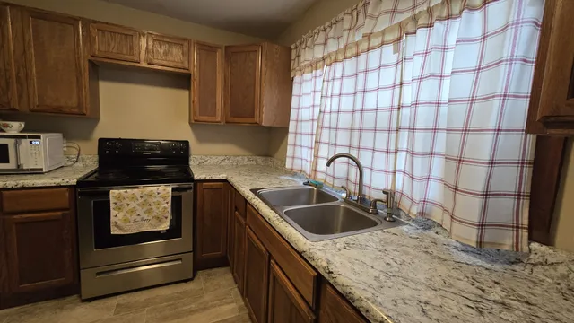 a kitchen with granite countertop a sink and a stove top oven
