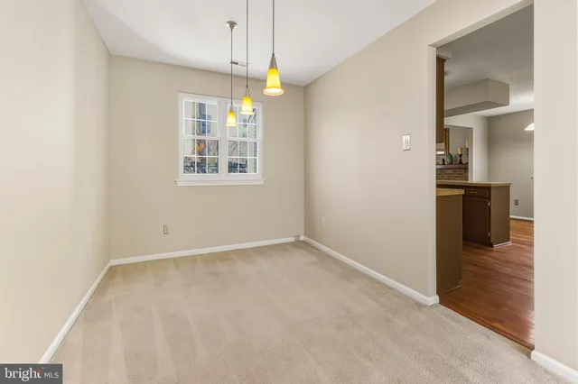 an empty room with chandelier fan and windows