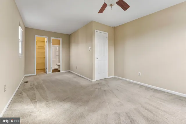 an empty room with a chandelier fan and windows