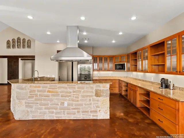a large kitchen with stainless steel appliances granite countertop a large counter top a stove and a sink