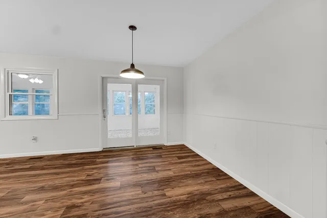 a view of an empty room with window and wooden floor