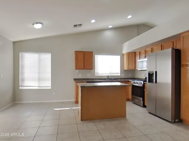 a large kitchen with stainless steel appliances granite countertop a stove a sink a refrigerator and a microwave