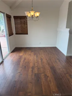 an empty room with wooden floor fireplace and windows