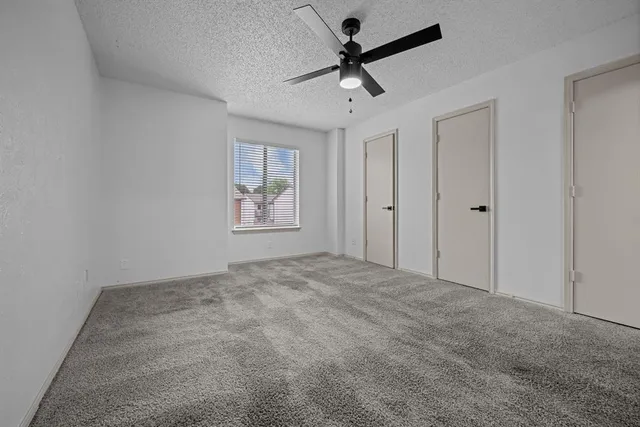 an empty room with windows and ceiling fan