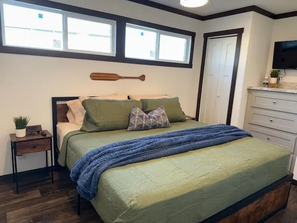 a bedroom with a bed and a flat tv screen on dresser