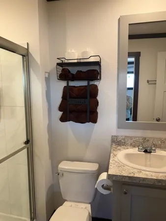 a bathroom with a granite countertop toilet sink and mirror