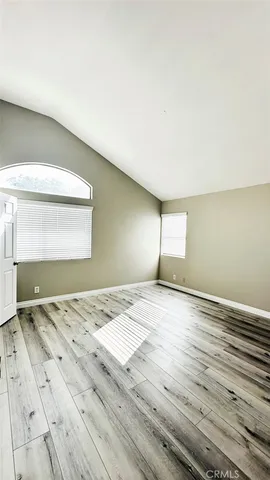a view of an empty room with wooden floor and a bathroom