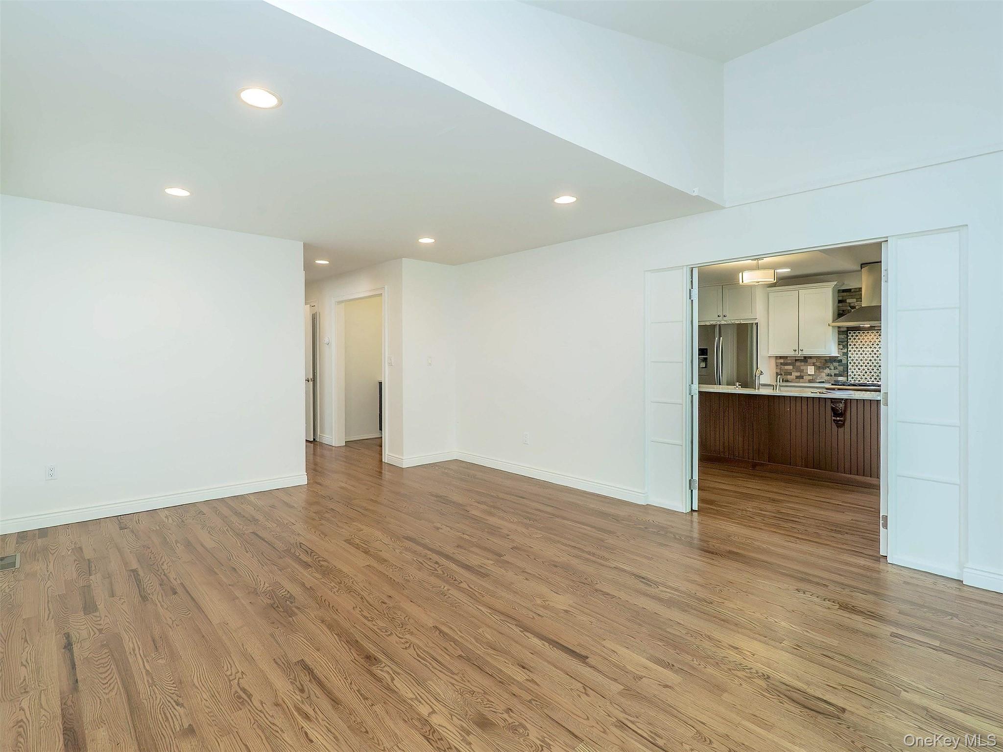 21 Marwood Road North Port Washington, NY 11050 - Photo 11 of 35 an empty room with wooden floor and a kitchen
