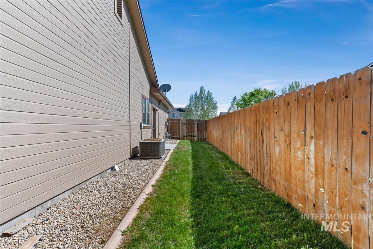 640 Southwest Miner Street Mountain Home, ID 83647 - Photo 10 of 35 Side yard featuring a wooden privacy fence, manicured lawn, and gravel landscaping alongside the home's siding