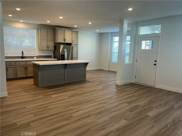 a kitchen with stainless steel appliances granite countertop a sink wooden cabinets and a wooden floor