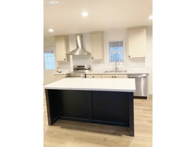 a kitchen with stainless steel appliances kitchen island a refrigerator sink and cabinets
