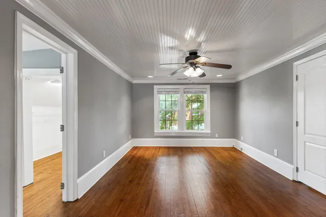 an empty room with wooden floor chandelier and windows