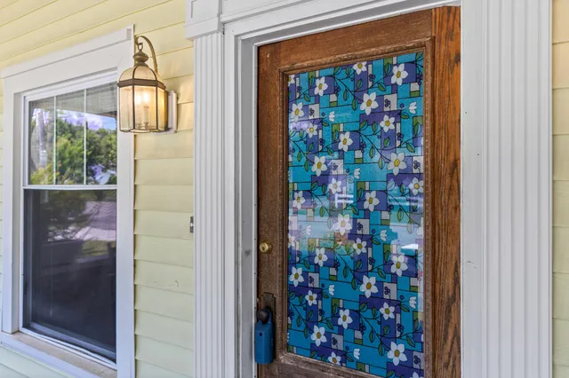 a view of an empty room with wooden floor and a kitchen