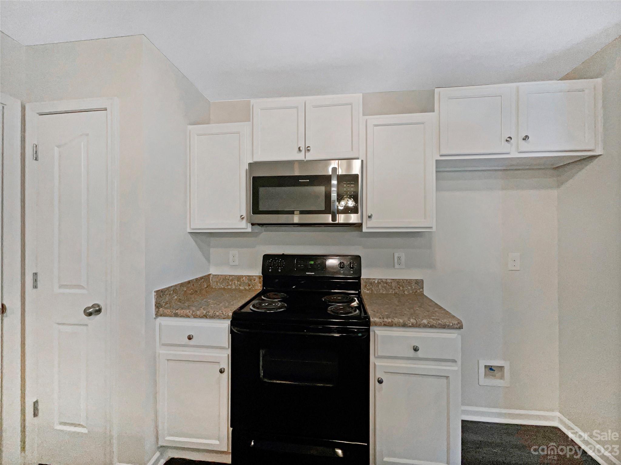 320 Peachtree Road Charlotte, NC 28216 - Photo 14 of 18 a kitchen with white cabinets and black appliances
