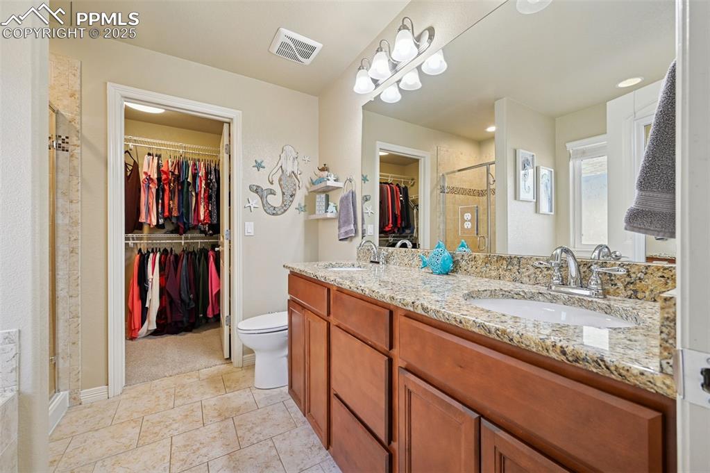 10214 Prairie Ridge Court Peyton, CO 80831 - Photo 20 of 42 a bathroom with a granite countertop sink a toilet and a mirror