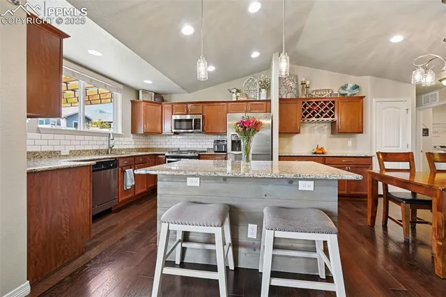 a large kitchen with stainless steel appliances granite countertop a stove a sink a dining table and chairs