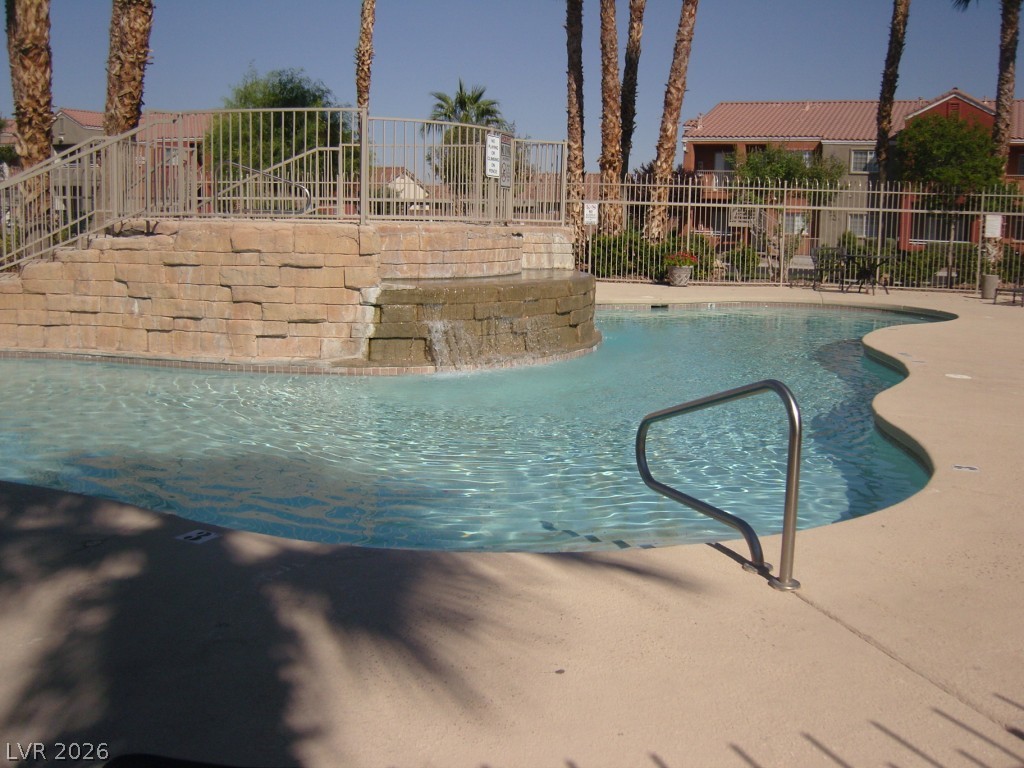 4730 East Craig Road, Unit 1073 Las Vegas, NV 89115 - Photo 17 of 18 An inviting community pool displays a stone waterfall feature under towering palm trees.
