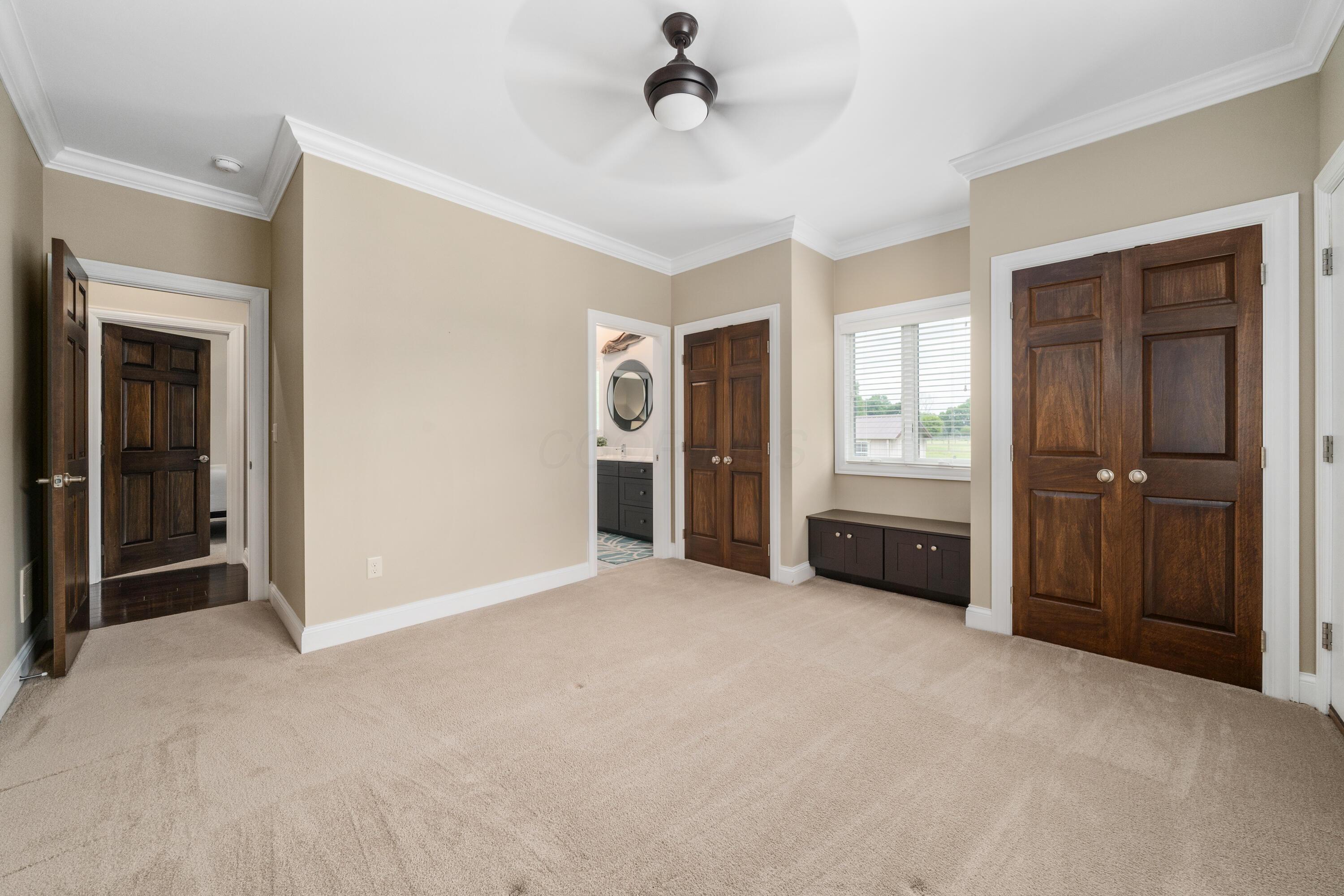 4640 Maynard Road Delaware, OH 43015 - Photo 54 of 91 Spacious carpeted room featuring crown molding, dark wood doors, a window with horizontal blinds, and a ceiling fan