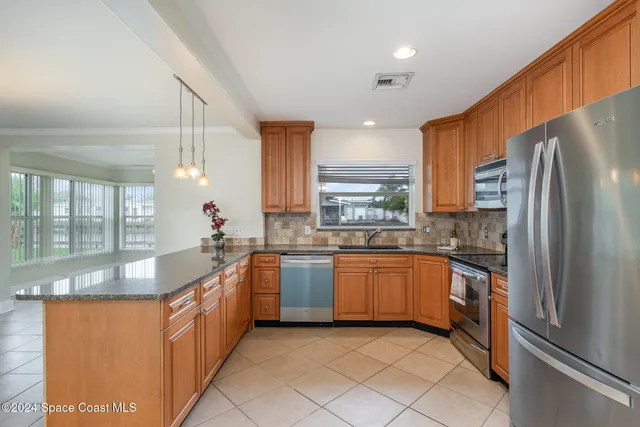 a large kitchen with granite countertop a sink and refrigerator