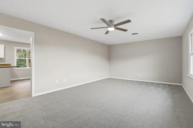 an empty room with a ceiling fan and windows