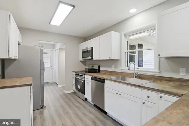 a kitchen with granite countertop stainless steel appliances a stove sink and cabinets