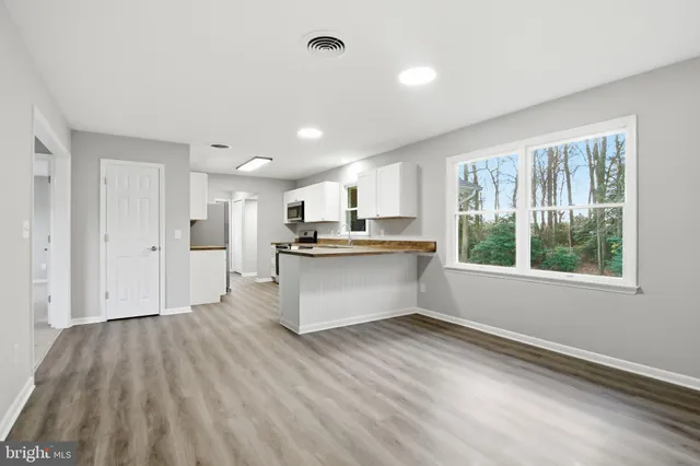 a kitchen with stainless steel appliances kitchen island wooden floors and white walls