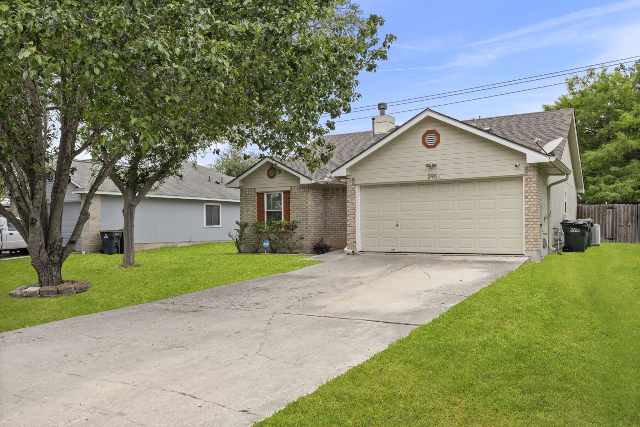 290 Bailey Loop Kyle, TX 78640 - Photo 5 of 33 Brick and siding exterior featuring an attached two-car garage, concrete driveway, and mature landscaping