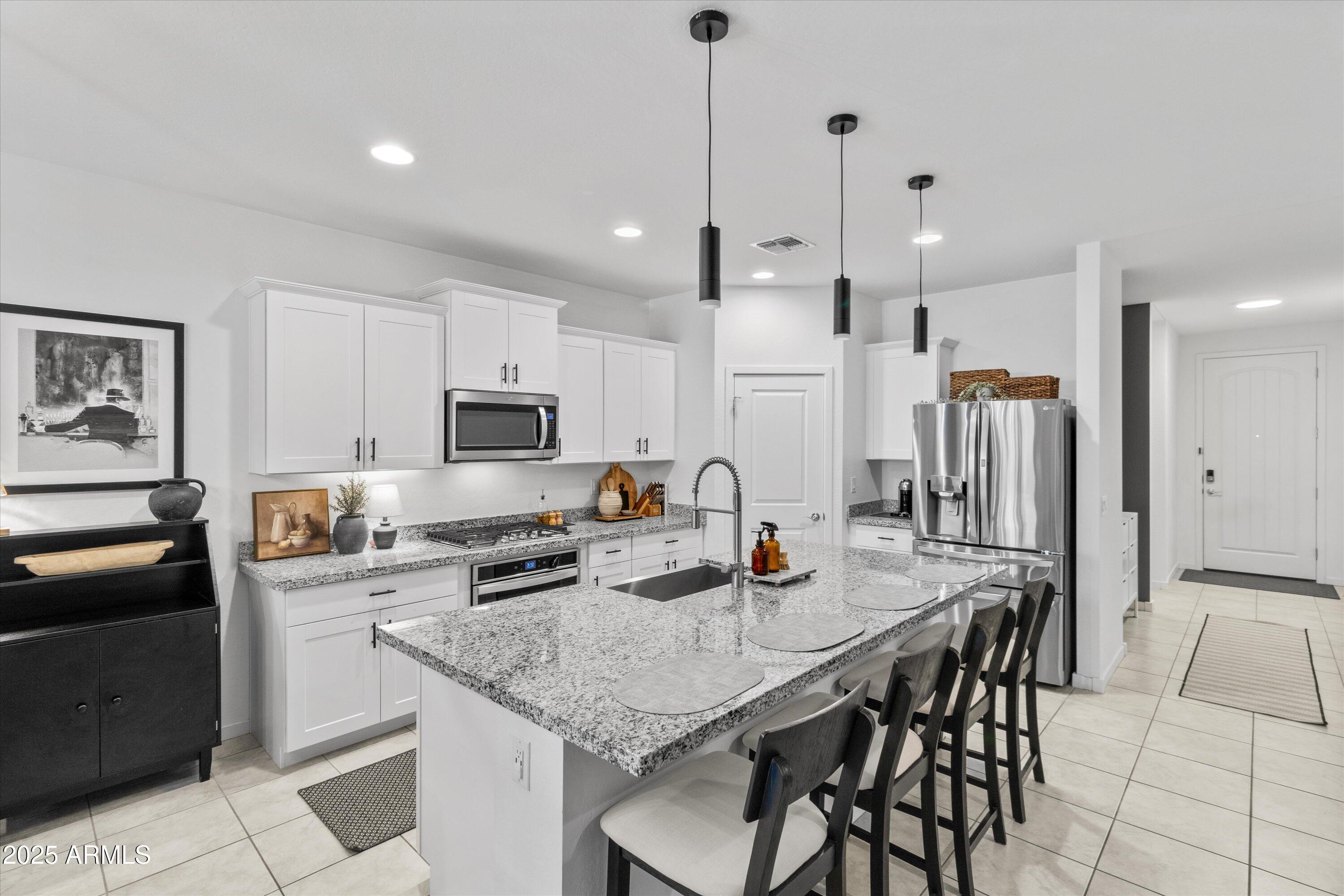 17970 West Pierson Street Goodyear, AZ 85395 - Photo 8 of 66 a kitchen with stainless steel appliances granite countertop a stove a refrigerator a kitchen island a table and chairs