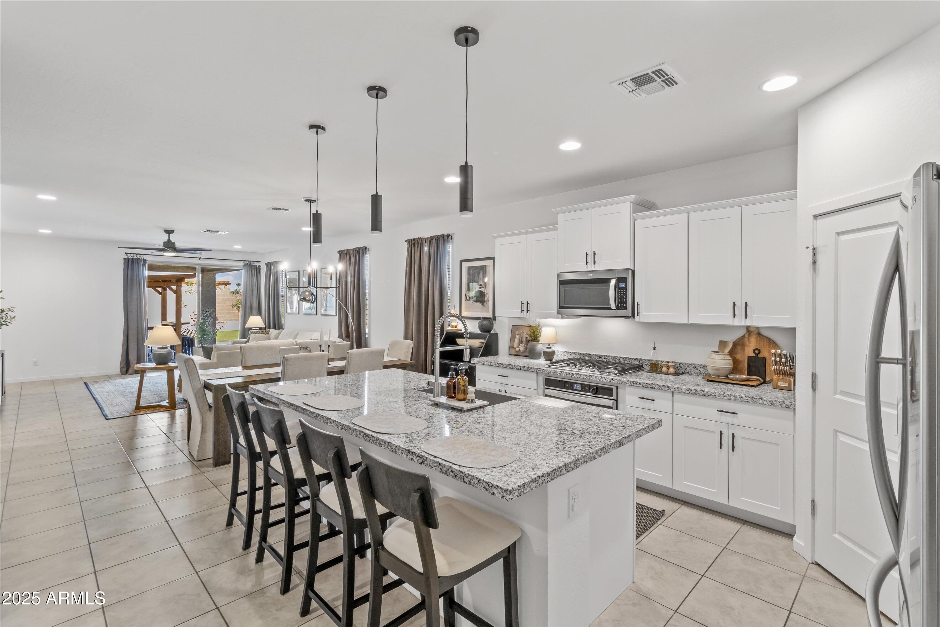 17970 West Pierson Street Goodyear, AZ 85395 - Photo 10 of 66 a kitchen with stainless steel appliances kitchen island granite countertop a table chairs stove and white cabinets