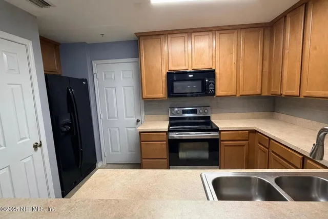 a kitchen with granite countertop a refrigerator stove and sink
