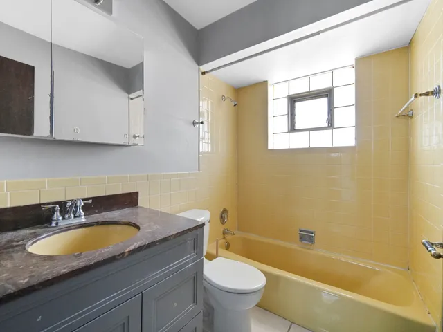 a bathroom with a granite countertop sink and a bathtub