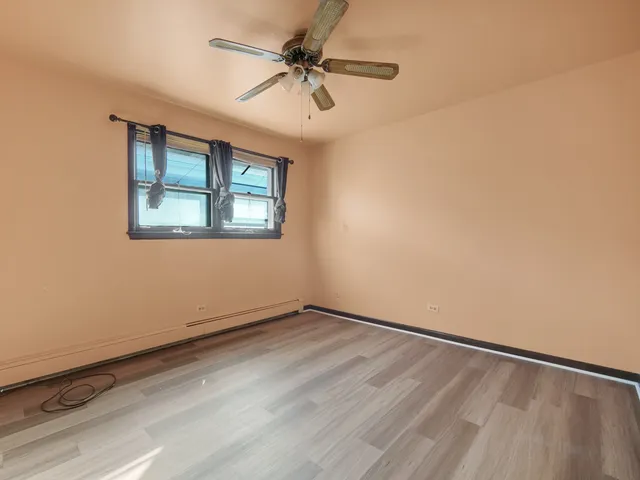 an empty room with a window and a fan
