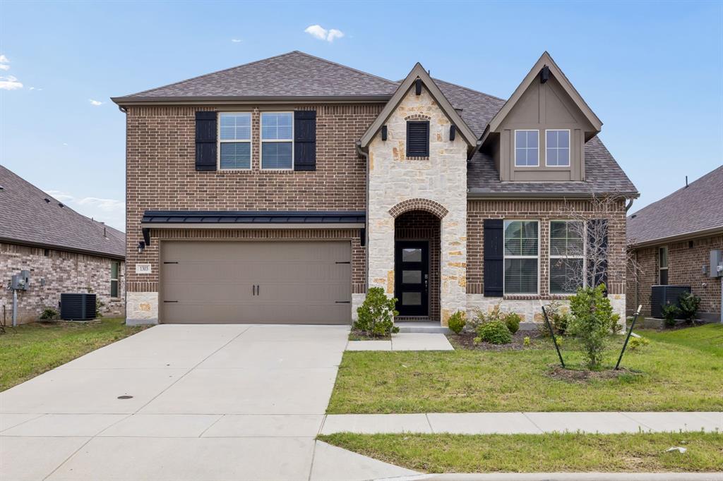 1303 Wheelwright Drive Forney, TX 75126 - Photo 1 of 39 Two-story brick and stone facade residence featuring a front entry garage with overhead awning