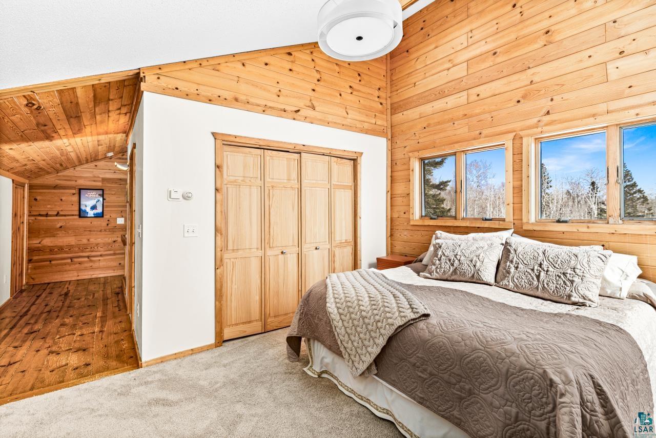 67 Snowshoe Trail Tofte, MN 55615 - Photo 6 of 42 Bedroom featuring wood walls, a closet, carpet, and a vaulted wood ceiling