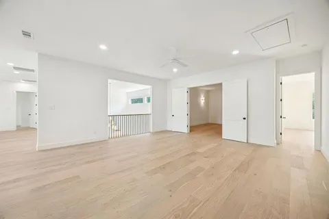 a view of an empty room with wooden floor and kitchen space