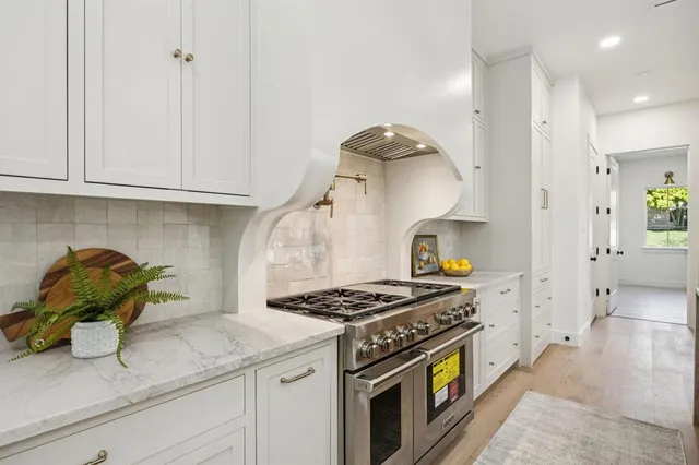 a kitchen with stainless steel appliances granite countertop a stove and a white cabinets