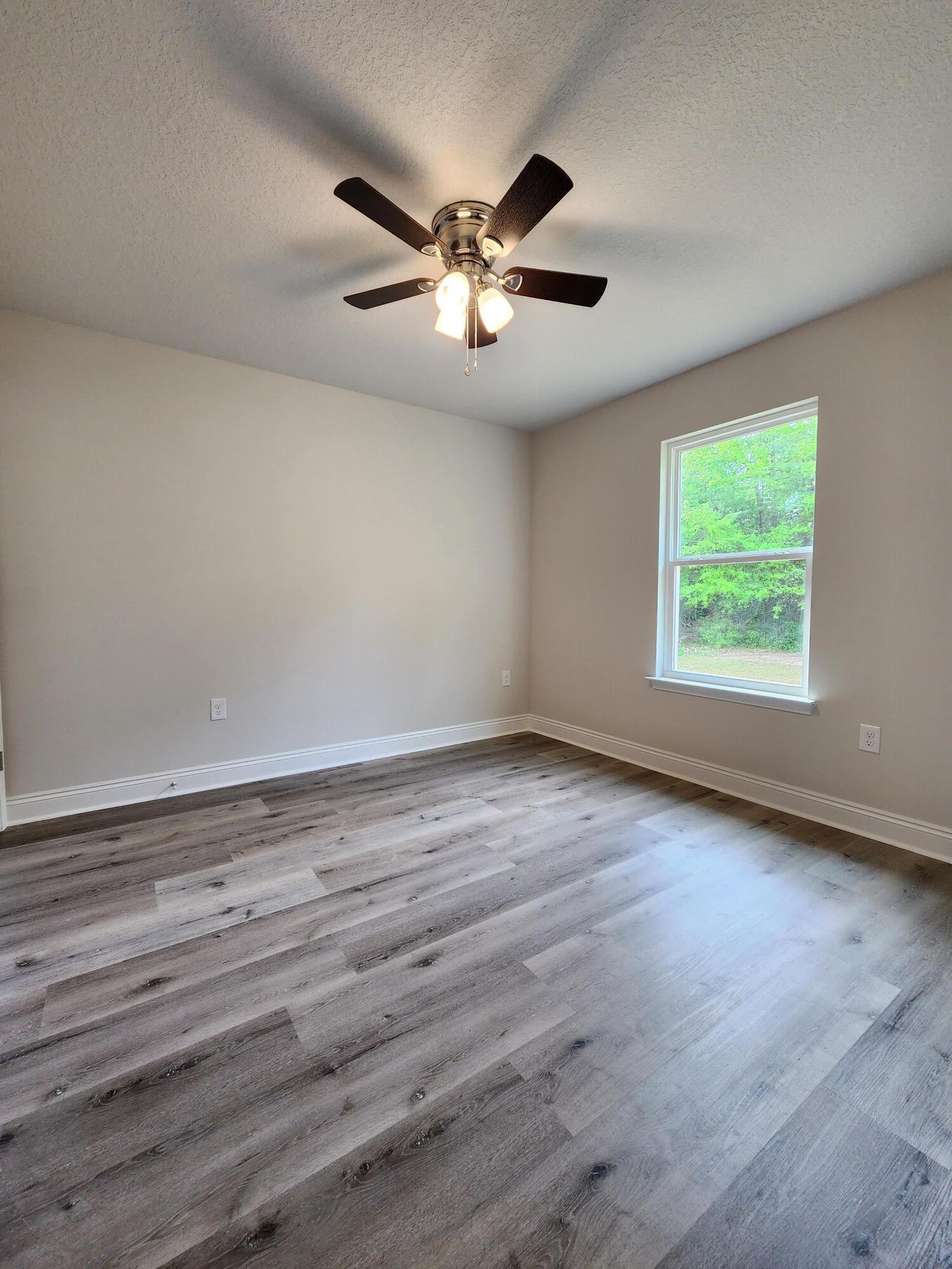 3168 Main Street Crestview, FL 32539 - Photo 16 of 18 an empty room with wooden floor fan and windows