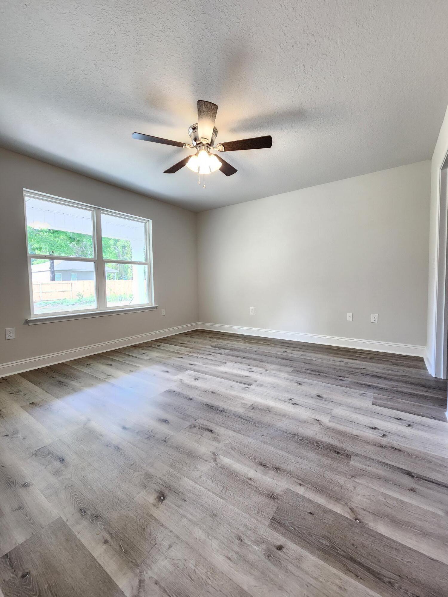 3168 Main Street Crestview, FL 32539 - Photo 10 of 18 an empty room with wooden floor ceiling fan and windows