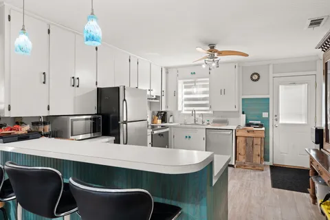 a kitchen with stainless steel appliances a dining table chairs stove refrigerator and microwave