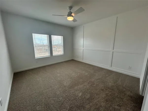 an empty room with chandelier fan and windows