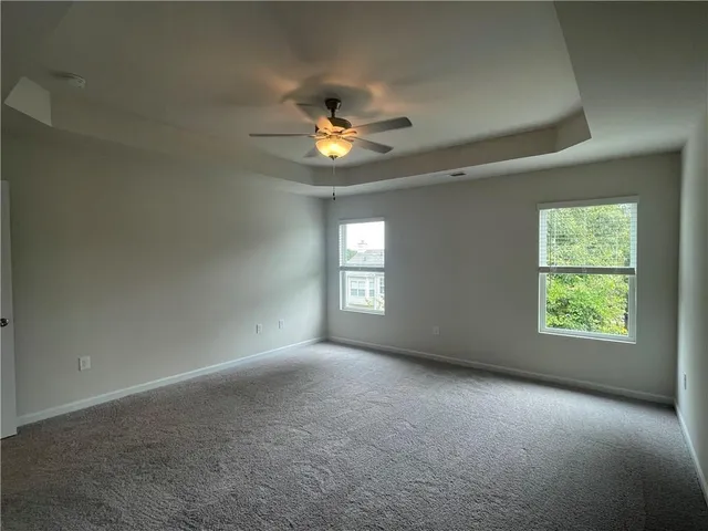 an empty room with windows and chandelier fan