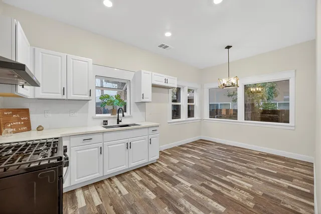a kitchen with a stove a microwave and white cabinets