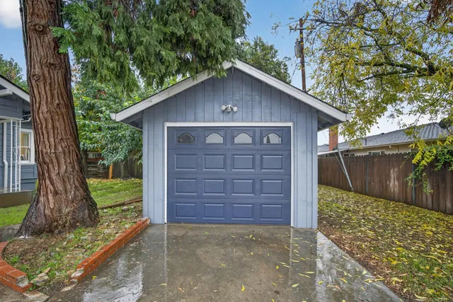 a view of a small house with a large tree and wooden fence