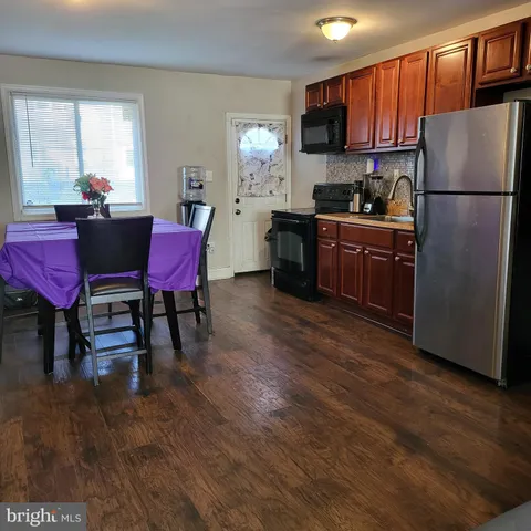 a kitchen with stainless steel appliances granite countertop a refrigerator a stove a sink dishwasher a dining table and chairs with wooden floor