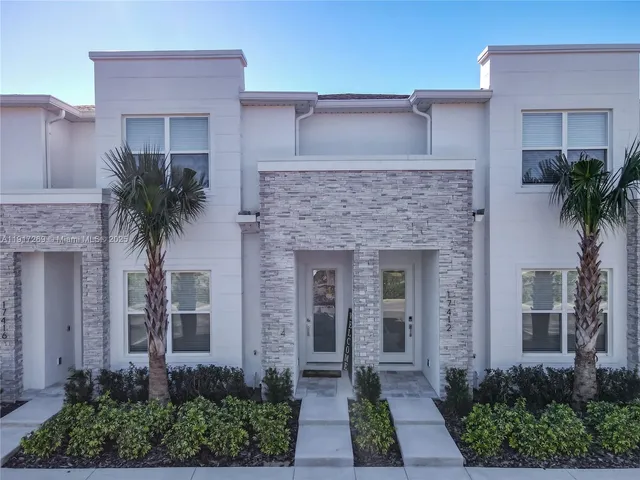 a front view of a house with yard and glass windows