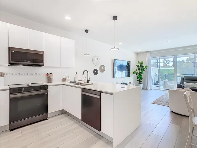 a kitchen with stainless steel appliances kitchen island granite countertop a stove top oven a sink a counter space and cabinets